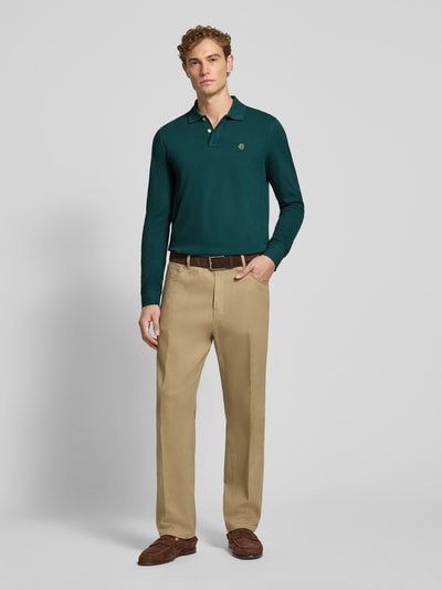 Männermodel trägt Regular Fit poloshirt uit puur katoen van MCNEAL in donkergroen met polokraag, knoopsluiting, labelstitching, shirt met lange mouwen, ruglengte bij maat M 73 cm, Ganzkörperansicht von vorne.