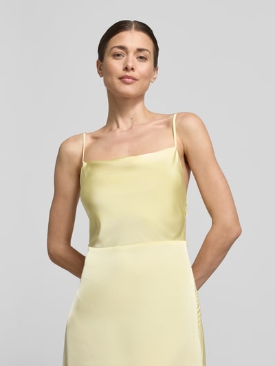 Vrouwenmodel draagt Maxikleid met spaghettibandjes model 'RAVENNA' van Vila, satijn, getailleerde fit, rechte hals, verstelbare bandjes, diepe rug, lichtgeel, gladde textuur, close-up bovenlichaam.