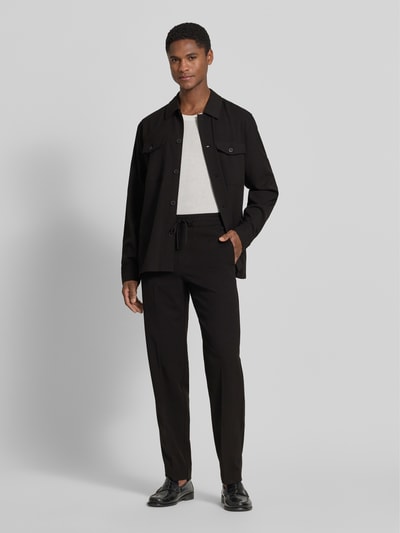 Männermodel trägt Relaxed Fit Sweatpants mit Viskose-Anteil von Lindbergh aus Elastischer-Material-Mix in Schwarz, mit Tunnelzug, Bügelfalten, Bundweite 41 cm, Innenbeinlänge 79 cm, Ganzkörperansicht von vorne.