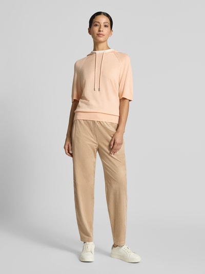 Frauenmodel trägt Stoffhose mit Stretch-Anteil von Marc Cain in Beige, Balloon Fit, Ziernähte, elastischer Bund, Ganzkörperansicht von vorne.