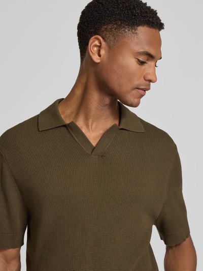 Männermodel trägt Regular Fit Strick-Poloshirt mit Strukturmuster Modell 'MOSVIK' von Casual Friday in Oliv mit V-Ausschnitt, Nahaufnahme Oberkörper.