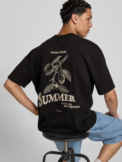 Männermodel trägt Oversized T-Shirt mit Label-Print von Pegador in Schwarz aus reiner Baumwolle, Rückenlänge 72 cm, Ganzkörperansicht Rückansicht.