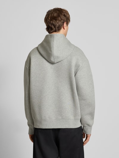 Męski model ma na sobie Hoodie mit Kapuze od Carhartt Work In Progress, bawełniany miks, luźny krój, szary, długość tyłu 70 cm, długość rękawa 62 cm, widok całopostaciowy z tyłu.