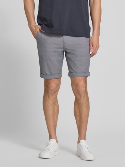 Männermodel trägt Slim Fit Chinoshorts aus Baumwoll-Mix Modell 'LUTON' von SELECTED HOMME, unifarben, feine Webstruktur, Ganzkörperansicht von vorne.