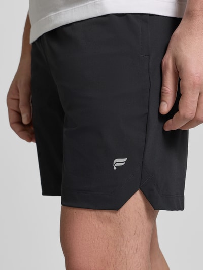 Männermodel trägt Regular Fit Shorts mit Logo-Print von Fabletics, Schwarz, elastischer Material-Mix, Nahaufnahme Oberschenkel.