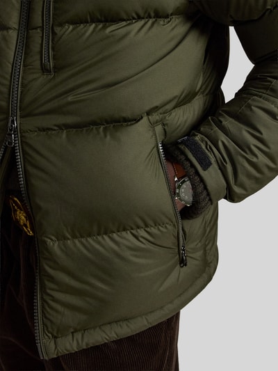 Männermodel trägt Regular Fit Daunenjacke mit Logo-Stitching von Polo Ralph Lauren in Olivgrün mit Reißverschluss, Nahaufnahme Oberkörper. Herren Daunenjacke von Polo Ralph Lauren