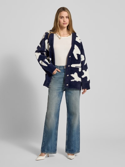 Frauenmodel trägt Comfort Fit Strickjacke mit Allover-Muster Modell 'JARDEN' von Essentiel Antwerp in Blau und Weiß, Materialverarbeitung: Strick, Passform: Comfort Fit, Verschluss: einreihige Knopfleiste, Details: überschnittene Schultern, V-Ausschnitt, langarm, aufgesetzte Eingrifftaschen; Ganzkörperansicht von vorne.