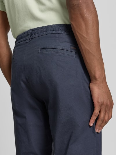 Männermodel trägt Tapered Chino aus Baumwoll-Mix Modell 'CHINO-TAPERED-DS-10' von BOSS Orange, Optik: Unifarben, Nahaufnahme Rückansicht.