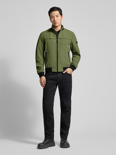Męski model nosi kurtkę Peuterey Jacke mit Stehkragen Modell 'POTOSI', mieszanka materiałów z dodatkiem streczu, krój regular fit, zamek błyskawiczny dwustronny, kolor oliwkowy, gładka tekstura, długość tyłu w rozmiarze M: 64 cm, szerokość ramion w rozmiarze M: 49 cm, szerokość w rozmiarze M: 59 cm, długość rękawów w rozmiarze M: 67 cm, całopostaciowy widok z przodu.