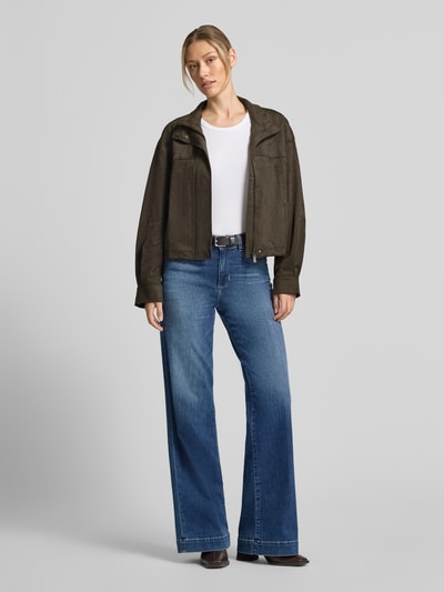 Frauenmodel trägt Oversized Jacke in Leder-Optik Modell 'Neila' von someday, olivgrün, kombiniert mit Jeans, Ganzkörperansicht von vorne. Elastischer Material-Mix, Stehkragen, Eingrifftaschen.