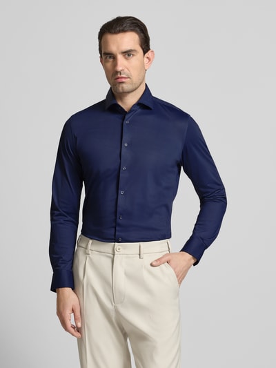 Männermodel trägt Slim Fit Business-Hemd mit Haifischkragen von SEIDENSTICKER, blau, glatte Struktur, material-mix met stretch, knoopsluiting, voorkant, bovenlichaam.