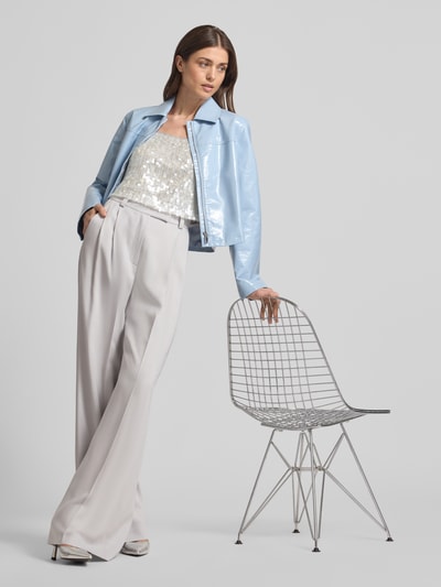 Frauenmodel trägt Cropped Trägertop mit Pailettenbesatz - curated by Vicky Heiler von SIC, glänzend, Kombination mit hellblauer Jacke, Ganzkörperansicht von vorne.