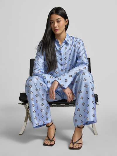 Vrouwenmodel draagt Seidenhose aus reiner Seide Modell 'LADATTI' van MM by Max Mara in lichtblauw met grafisch patroon, losse fit, satijnen textuur, elastische tailleband, detailopname voorkant.