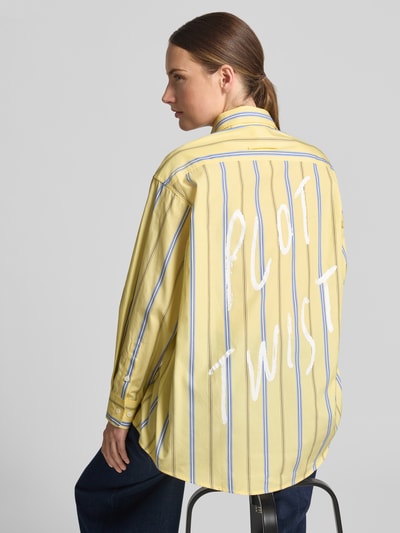 Frauenmodel trägt Relaxed Fit Langarmbluse aus reiner Baumwolle Modell 'MCODAMA' von MAX&Co. in Gelb mit blauen Streifen und weißem Schriftzug, Damen Langarmbluse von MAX&Co., Ganzkörperansicht Rückansicht.