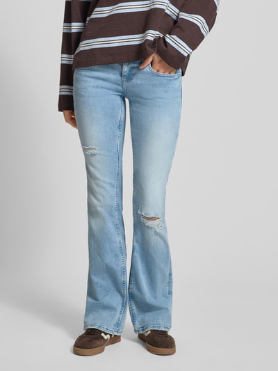Frauenmodel trägt Flared Fit Jeans im Used-Look von Gina Tricot in hellem Blau, 5-Pocket-Design, Baumwoll-Mix, Knopf-Reißverschluss, Ganzkörperansicht von vorne.
