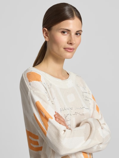 Frauenmodel trägt Pullover mit Strasssteinbesatz von monari in Creme mit Orange, Baumwoll-Mix, gerader Schnitt, Nahaufnahme Oberkörper.
