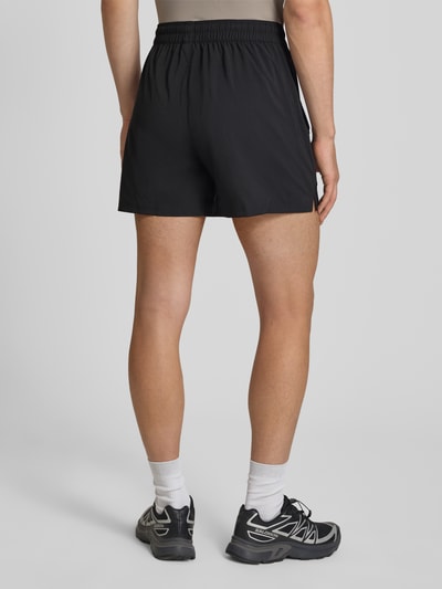 Männermodel trägt schwarze Regular Fit Sportshorts mit Logo-Print Modell 'TAD ESSENTIALS' von PUMA Performance, Ganzkörperansicht Rückansicht.
