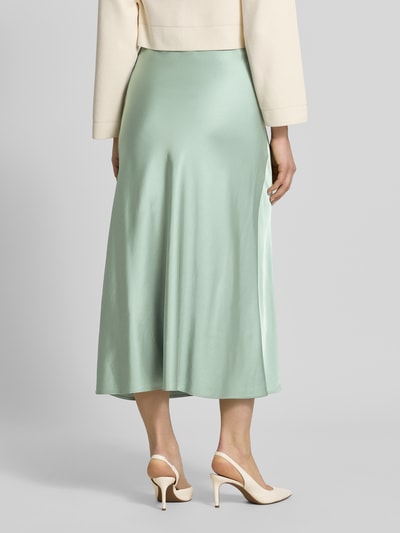 Frauenmodel trägt Midirock in schimmerndem Design von comma in Mintgrün, gerader Schnitt, Material-Mix mit Viskose-Anteil, Ganzkörperansicht Rückansicht.