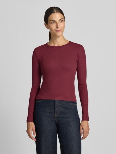 Frauenmodel trägt Slim Fit Langarmshirt aus Baumwoll-Mix Modell 'CHLOE' von VERO MODA, dunkelrot, glatte Textur, Ganzkörperansicht von vorne.