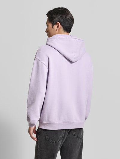 Männermodel trägt Hoodie mit Logo Modell 'PLIZZY' von American Vintage, bawełna, krój relaxed fit, kieszeń kangurka, długość tyłu 66 cm, długość rękawów 60 cm, tylna, Ganzkörperansicht Rückansicht.