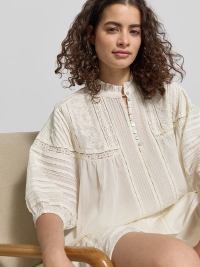 Modelka prezentuje Relaxed Fit Bluse mit Stitchings und Drapierungen von Jake*s Casual, kremowy bawełniano-wiskozowy materiał, stójka, guziki, koronka, szwy ozdobne, drapowania, rękaw 3/4, długość pleców 62 cm, długość rękawa 25 cm w rozmiarze 38, zbliżenie na górną część ciała.