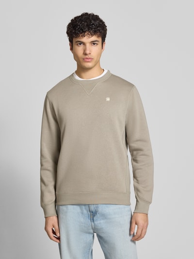 Männermodel trägt Sweatshirt mit Rundhalsausschnitt und Label-Stitching von G-Star Raw in Beige, Baumwoll-Mix, Regular-Fit, Ganzkörperansicht von vorne. Rückenlänge bei Größe M 67 cm, Ärmellänge 66 cm.