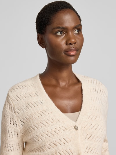 Vrouwenmodel draagt Strickjacke mit V-Ausschnitt und Knopfleiste van MORE, lichtbeige met wol, gebreid patroon, regular fit, labeldetail, Nahaufnahme bovenlichaam