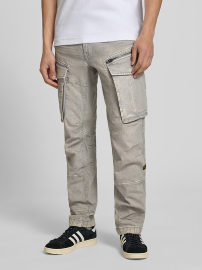 Męski model nosi Regular Tapered Fit Hose mit Cargotaschen Modell 'Rovic' von G-Star Raw, bawełna z elastanem, krój tapered fit, styl używany, kieszenie cargo, szerokość w rozmiarze 32/32: 44 cm, długość nogawki od wewnątrz: 78 cm, kolor szary, całość gładka, widok całej sylwetki z przodu.