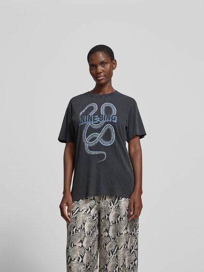 Frauenmodel trägt Slim Fit T-Shirt aus Reiner Baumwolle von Anine Bing mit Label-Print und Rundhalsausschnitt, ganzkörperansicht von vorne.