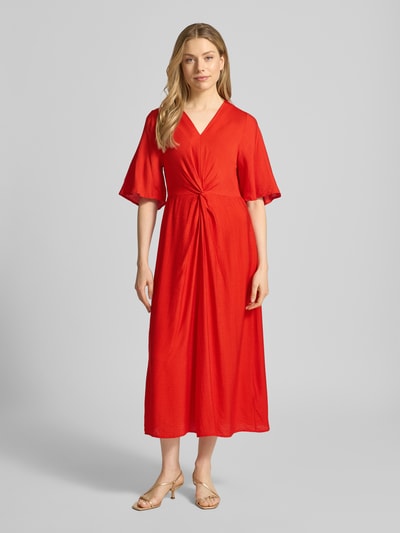 Frauenmodel trägt Midikleid aus Viskose-Mix mit Schmetterlingsärmel Modell 'MELDA' von ICHI, taillierter Schnitt, V-Ausschnitt, Ganzkörperansicht von vorne.