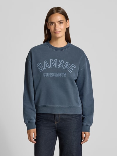 Modelka kobieca ma na sobie Sweatshirt mit Label-Print Modell 'SAVAN' od Samsøe Samsøe z bawełny, kolor niebieski, prosty krój, widok całej sylwetki z przodu.