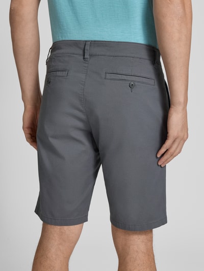 Männermodel trägt Regular Fit Bermudas aus Baumwoll-Mix Modell 'PHOENIX' von s.Oliver RED LABEL, efekt: jednolity kolor, krój regular fit, długość: krój krótki, szlufki na pasek, zapięcie na guzik i zamek błyskawiczny, 5 kieszeni, splot twill, mieszanka bawełny; Ganzkörperansicht Rückansicht.
