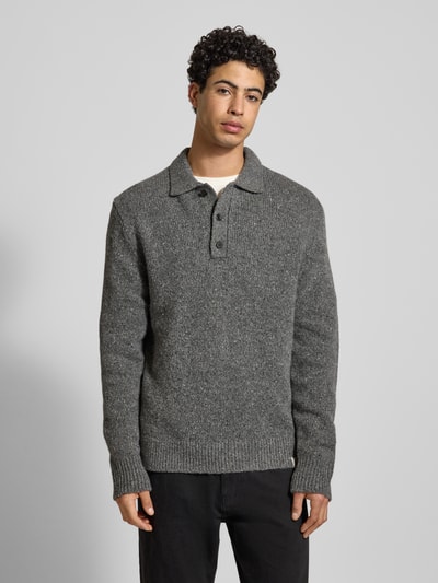 Männermodel trägt Strickpullover aus Woll-Mix mit Polokragen von Calvin Klein Jeans in Grau, Regular-Fit, Knopfleiste, Label-Detail, Ganzkörperansicht von vorne. Rückenlänge bei Größe M 76 cm, Ärmellänge 72 cm.