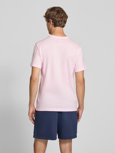 Männermodel trägt Regular Fit T-Shirt aus reiner Baumwolle von Nike in Hellrosa, glatte Textur, Ganzkörperansicht Rückansicht.