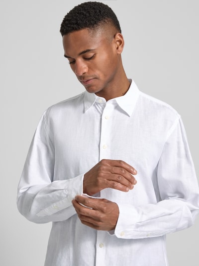 Männermodel trägt Regular Fit Freizeithemd aus Leinen-Baumwoll-Mix Modell 'CLAY LINENBLEND' von SELECTED HOMME, Melange-Optik, Weiß, durchgehende Knopfleiste, Kentkragen, 2-Knopf-Manschette, Flammgarn, Nahaufnahme Oberkörper.