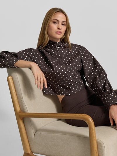 Frauenmodel trägt Kurze voluminöse Bluse - curated by Mary Braun von Style Icon Collection aus brauner Baumwolle mit weißen Punkten, Stehkragen und Knopfleiste, Regular Fit, Nahaufnahme Oberkörper.