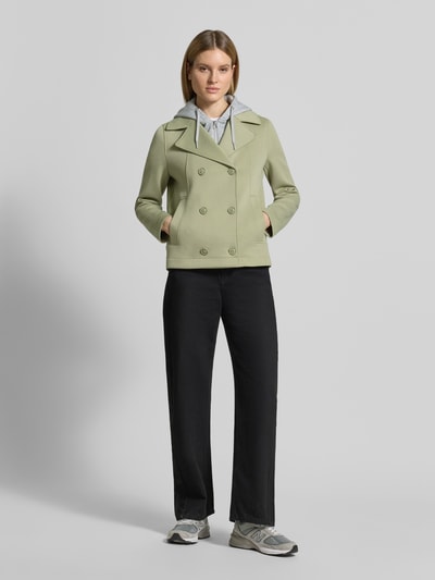 Vrouwenmodel draagt Regular Fit sweatjack met viscose van s.Oliver RED LABEL in lichtgroen, met dubbele knoopsluiting, reverskraag, capuchon, lange mouw, zijsteekzakken, materiaalverwerking sweat, ganzichaamsaanzicht van voren.