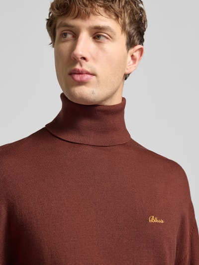 Männermodel trägt Loose Fit Rollkragenpullover aus Woll-Mix von BLKVIS in Braun mit Label-Stitching, Nahaufnahme Oberkörper.