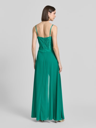 Frauenmodel trägt Jumpsuit mit Spitze und Spaghettiträgern von Rinascimento in Grün, ausgestellt, strukturierter Stoff, Rückseite, Ganzkörperansicht Rückansicht. Taillierter Schnitt, Herz-Ausschnitt, verstellbare Träger, Rückseitiger Reißverschluss, Maße S: Rückenlänge 20 cm, Brustweite 37 cm, Gesamtlänge 135 cm, Innenbeinlänge 112 cm.