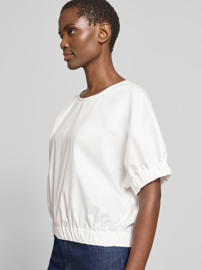 Frauenmodel trägt Blusenshirt mit Rundhalsausschnitt von FREE/QUENT, Material-Mix mit Baumwoll-Anteil, Gerader-Schnitt, 1/2-Arm, Rückenlänge 52 cm, Ärmellänge 23 cm, einfarbig, glatte Textur, Ganzkörperansicht von der Seite.