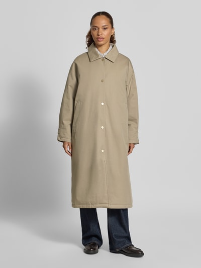 Vrouwenmodel draagt lange jas van katoenmix Model 'Free' van g-lab in beige met platte kraag en knoopsluiting, regular fit, elastische mouwboorden, ruglengte maat S 116 cm, schouderbreedte 58 cm, borstwijdte 66 cm, mouwlengte 51 cm, geheel frontaal zicht.