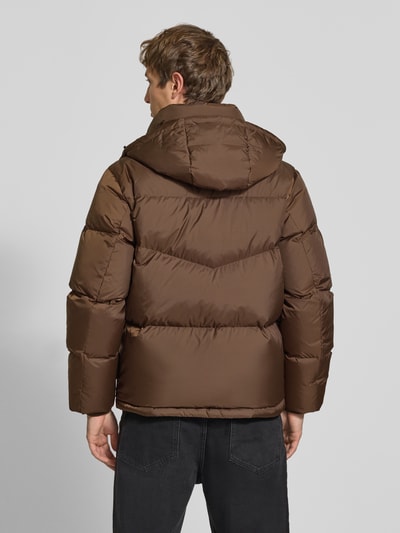 Männermodel trägt Regular Fit Daunenjacke mit Kapuzenkragen von Marc O'Polo DENIM in Braun, gesteppte Oberfläche, Ganzkörperansicht Rückansicht.
