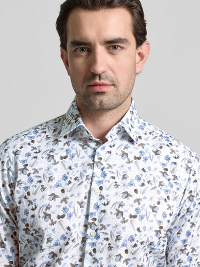 Männermodel trägt Regular Fit Business Hemd aus Baumwolle mit Kentkragen von Christian Berg Men, floral, wit met blauwe en grijze tinten, knoopsluiting, pure katoen, kentkraag, regular fit, borststuk in detail, Nahaufnahme Oberkörper.