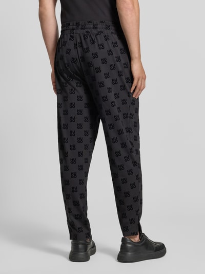 Männermodel trägt Regular Fit Sweathose aus Baumwoll-Mix von HUGO, dunkle Farben, lockere Passform, Muster, Ganzkörperansicht Rückansicht, Herren Sweathose von HUGO.
