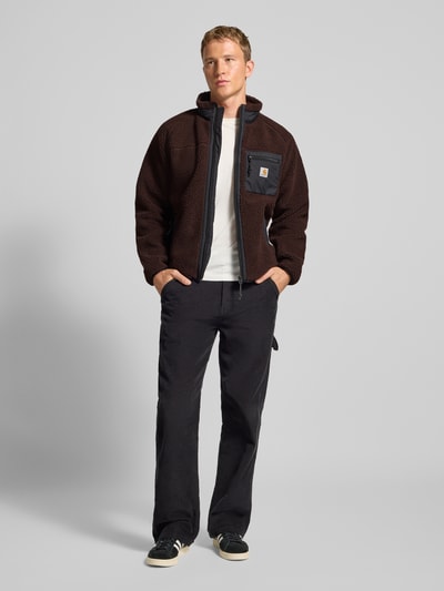 Männermodel trägt Fleecejacke mit Brusttasche Modell 'PRENTIS LINER' von Carhartt Work In Progress in Braun mit Regular Fit, Ganzkörperansicht von vorne.