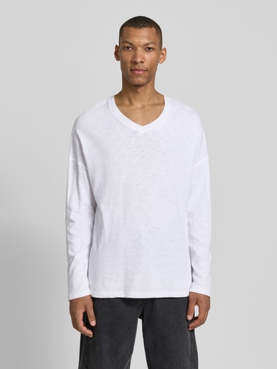 Männermodel trägt Longsleeve mit überschnittenen Schultern Modell 'SONOMA' von American Vintage in Weiß, reine Baumwolle, V-Ausschnitt, Ganzkörperansicht von vorne.