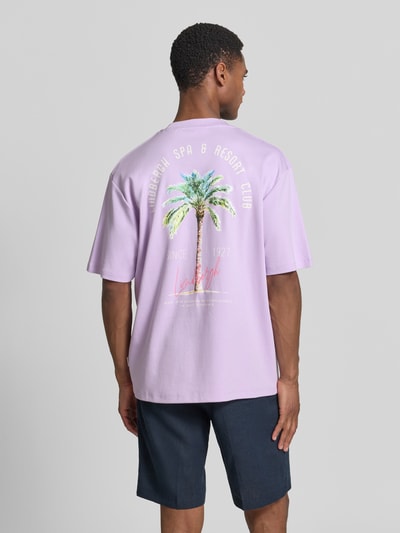 Männermodel trägt Oversized T-Shirt mit Label-Print von Lindbergh in Helllila, Reine Baumwolle, Rundhalsausschnitt, Rückenlänge 70 cm, Ganzkörperansicht Rückansicht.