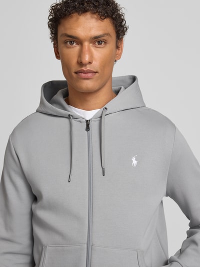 Männermodel trägt Sweatjacke mit Kapuze von Polo Ralph Lauren aus Baumwoll-Elasthan-Mix, Regular-Fit, Hellgrau, Nahaufnahme Oberkörper.