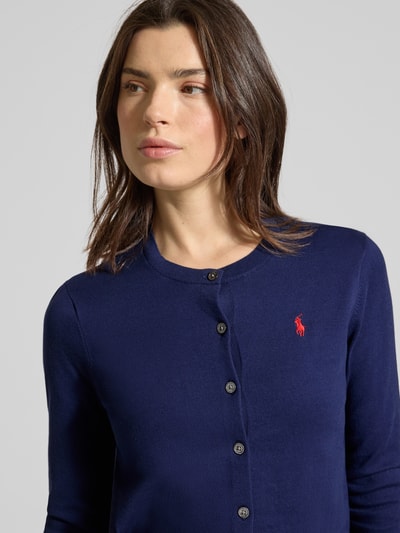 Frauenmodel trägt Regular Fit Strickjacke aus Baumwoll-Mix von Polo Ralph Lauren in Dunkelblau mit Logo-Stitching und Knopfleiste, Nahaufnahme Oberkörper.
