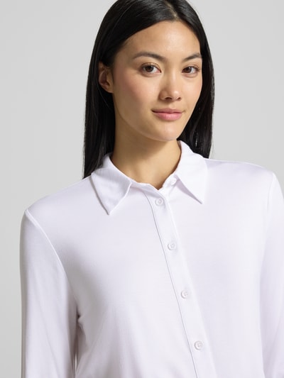 Frauenmodel trägt weiße Slim Fit Hemdbluse aus Viskose-Mix von COMMA mit Knopfleiste und Hemdblusenkragen, Nahaufnahme Oberkörper.